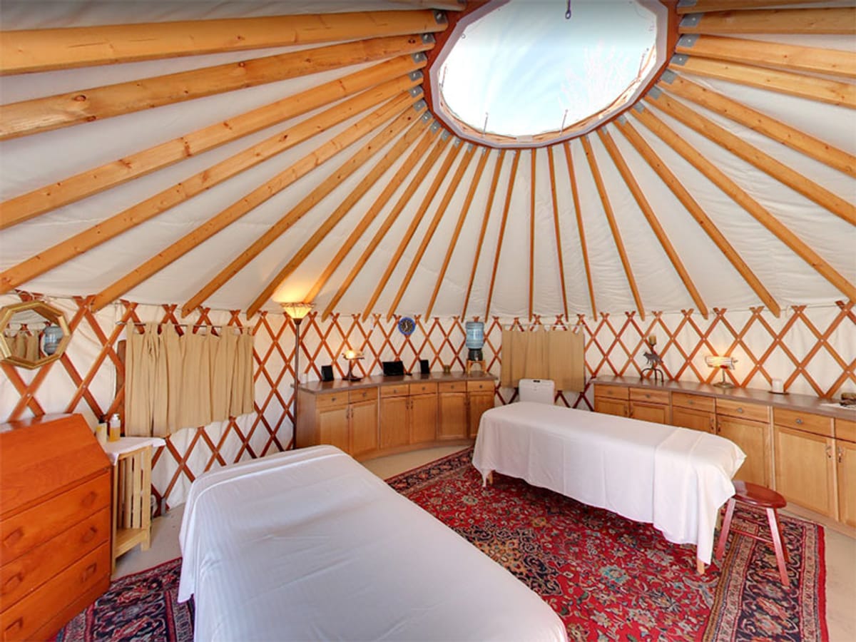 Cozy yurt interior with two massage tables and warm wooden accents.