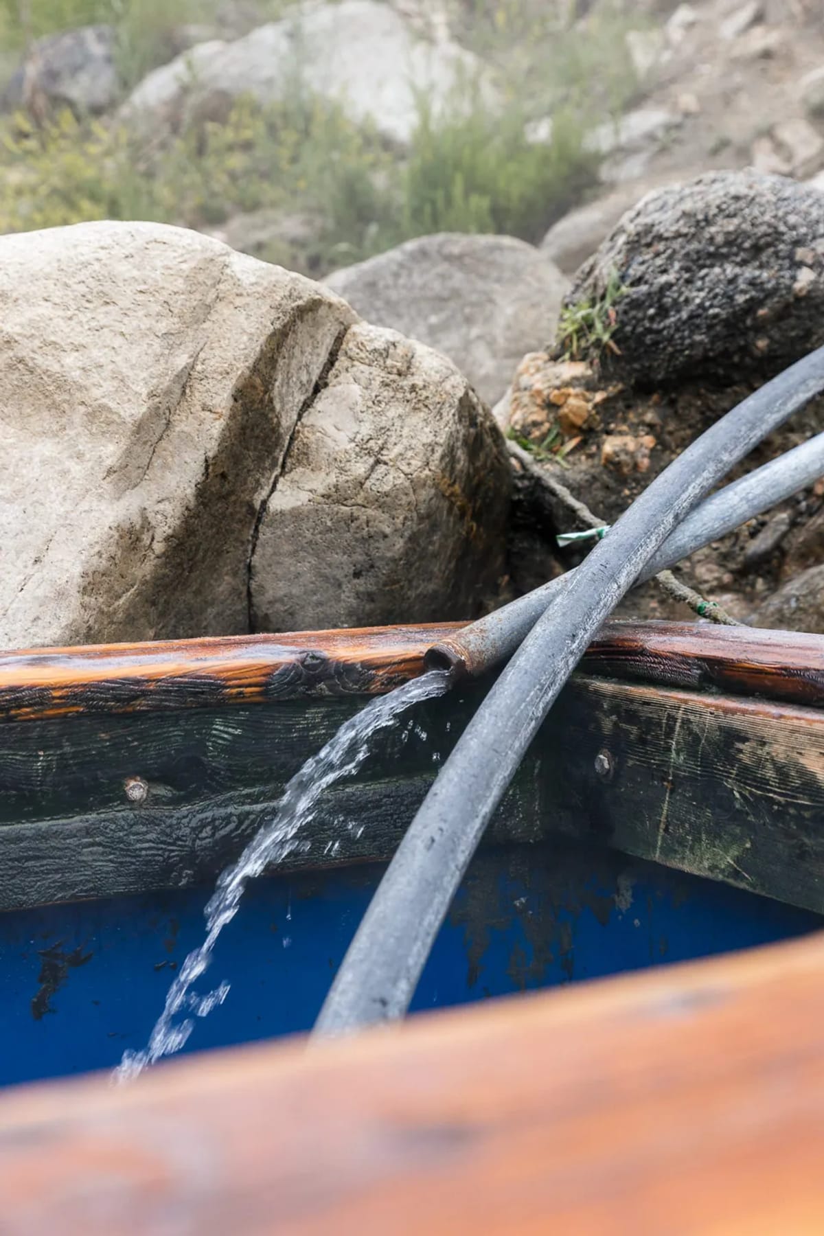 Close up on hot natural spring water running out of a pipe into a blue soaking tub at Sunbeam Hot Springs